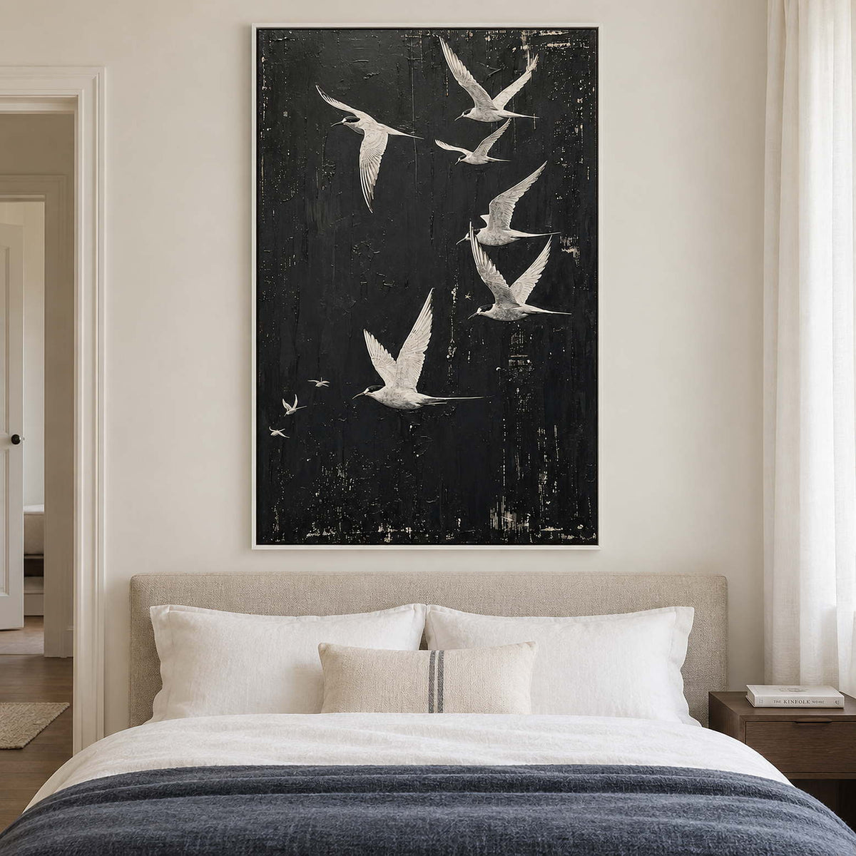 White birds flying across a charcoal-black sky in a white frame, displayed above a bed.