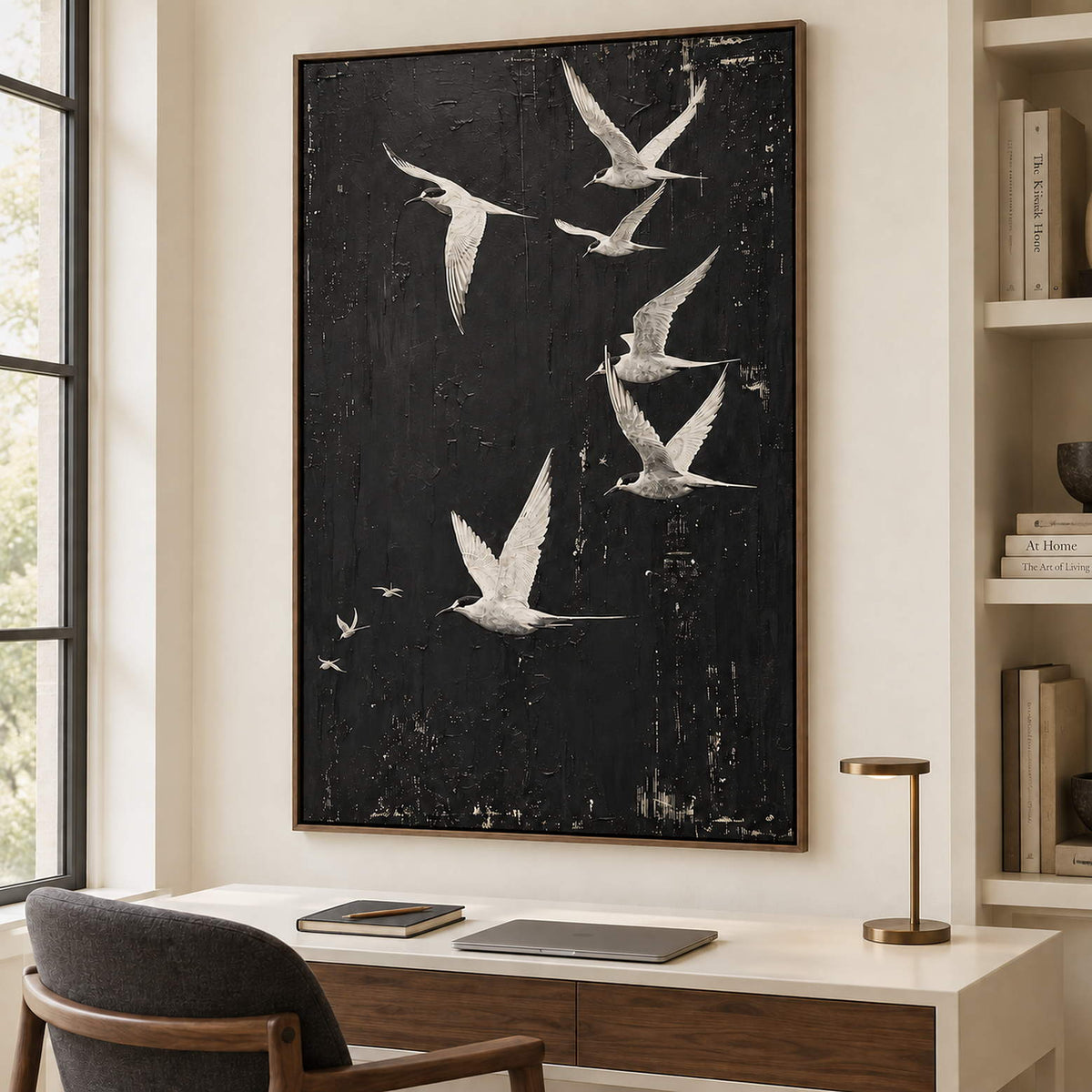White birds flying across a charcoal-black sky in a brown wood frame, displayed in a home office.