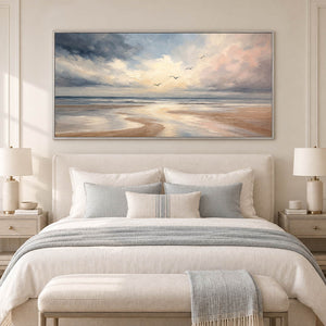 Hand-painted coastal wall art with pale blue, blush, and ivory shoreline, displayed in a bedroom in a silver frame.