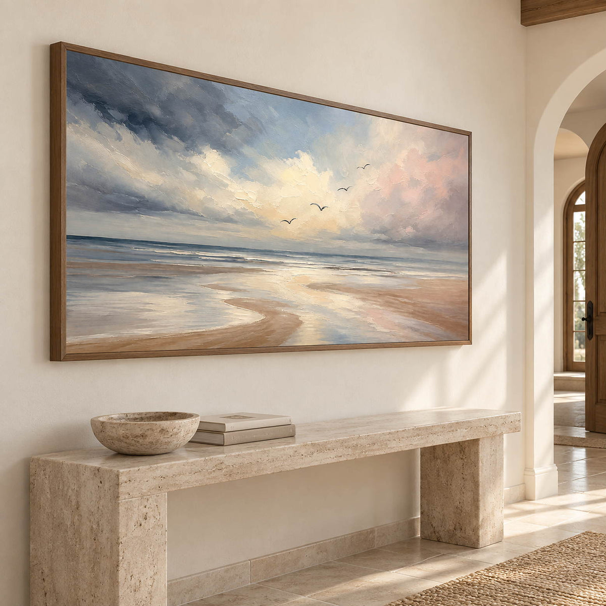 Hand-painted coastal wall art with pale blue, blush, and ivory shoreline, displayed in an entryway in a brown wood frame.