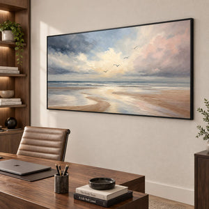 Hand-painted coastal wall art with pale blue, blush, and ivory shoreline, displayed in a study in a black frame.