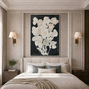 White framed floral artwork above a neutral bed with layered pillows and wall lamps.