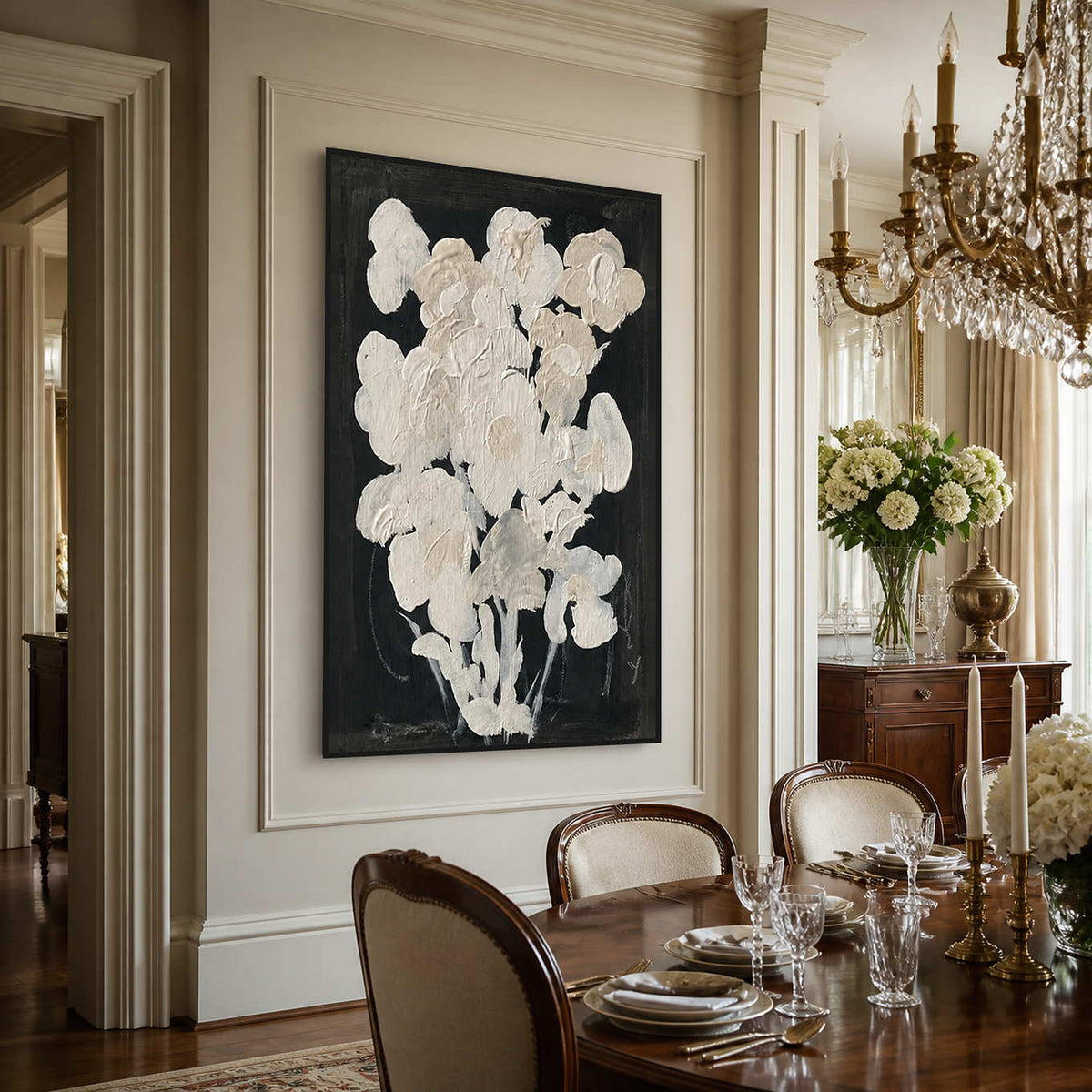 Black framed cream floral artwork beside a wooden dining table under a crystal chandelier.