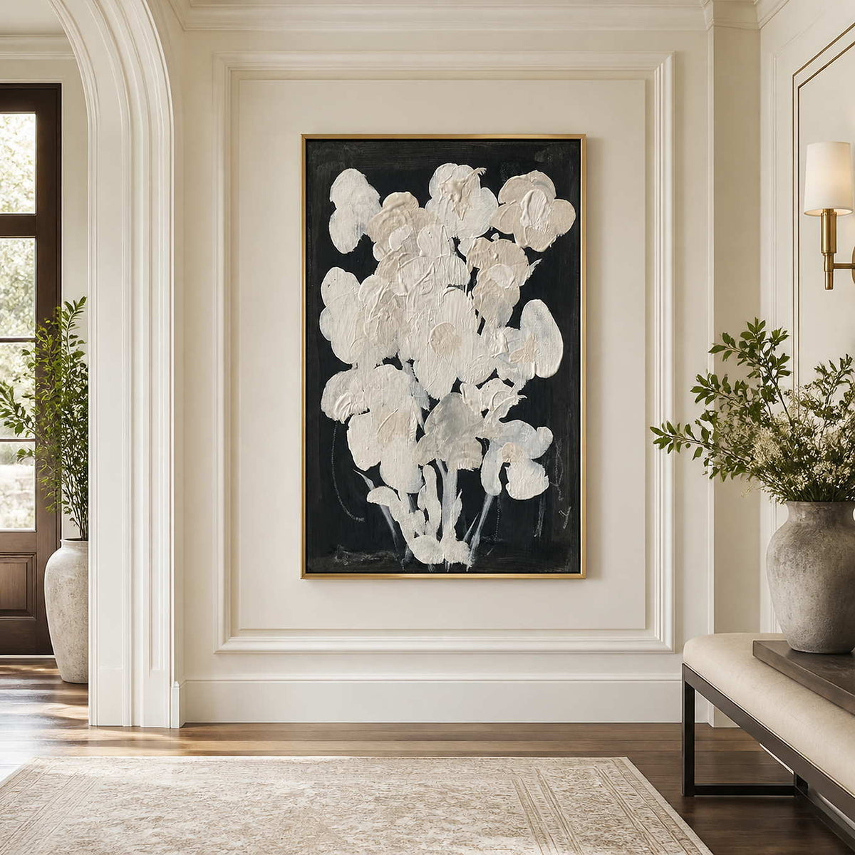 Gold framed cream floral artwork on a bright hallway wall near an arched doorway.