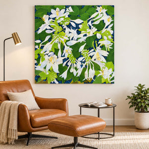 Beside a reading chair, an artwork with no outer frame shows white flowers and broad green leaves over a deep blue ground.