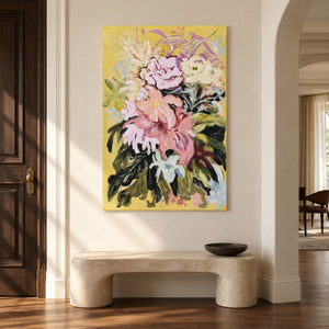 Artwork showing large pink and cream flowers with dark green leaves on a warm yellow ground in an entryway above a console or bench, with no outer frame.