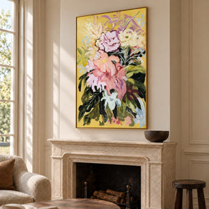 Large pink and cream flowers with dark green leaves on a warm yellow ground in an artwork with a gold-colored frame, displayed above a fireplace.