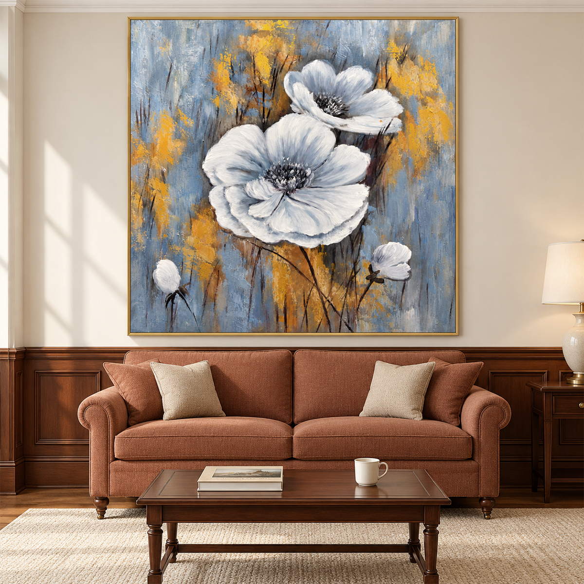 Artwork showing two large white flowers and small buds on a blue-gray ground with ochre marks in a living room above seating, with a gold-colored frame.