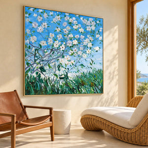 Artwork showing white flowering branches against blue sky above green grass in a sunlit seating area, with a gold-colored frame.