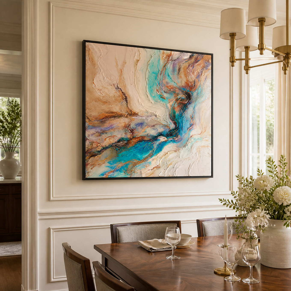 Black framed turquoise abstract artwork beside a dining table set with wine glasses.