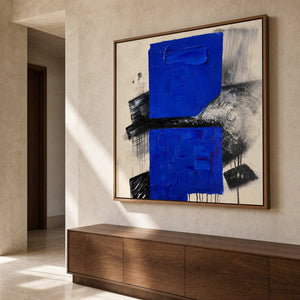 Square blue textured painting above a wood console in an entryway.