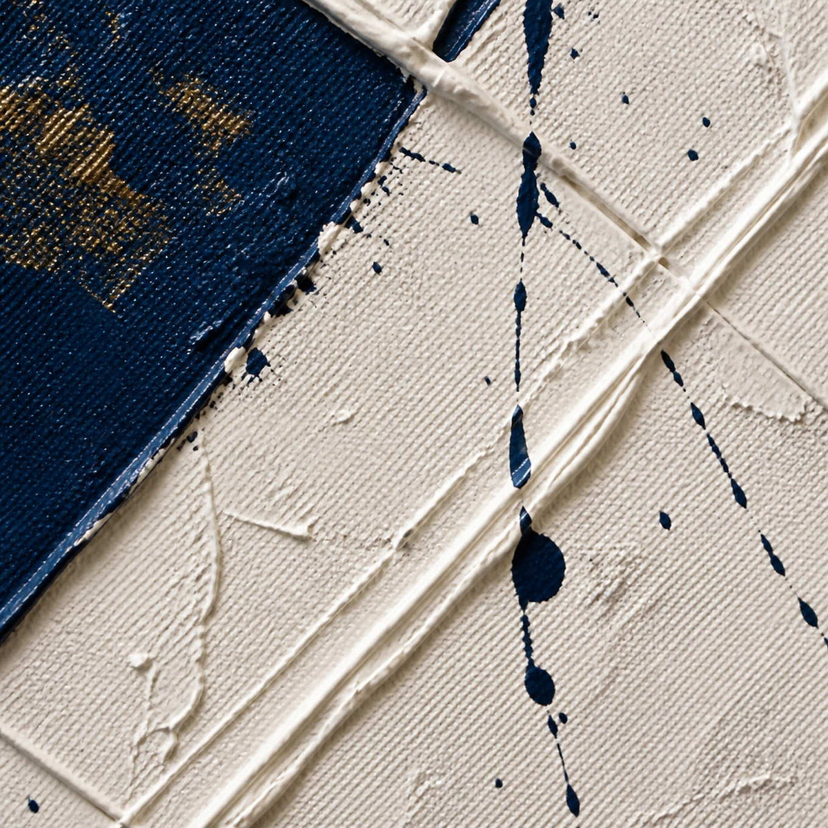 Close-up of raised ivory plaster, navy paint splatters, and subtle metallic texture.
