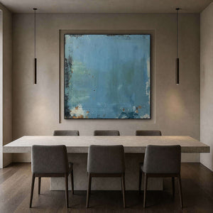Muted blue abstract canvas above a dark wood dining table.