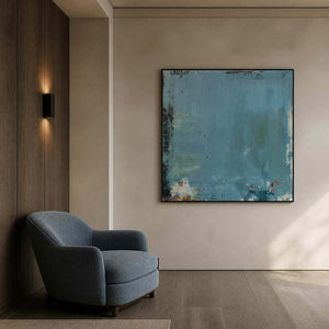 Muted blue wall art beside a soft chair in a sitting nook.
