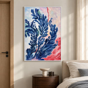 In a bedroom near the bed, an artwork with a white frame shows branching deep blue forms curling upward over pale pink, cream and red.