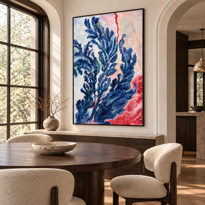 Artwork showing branching deep blue forms curling upward over pale pink, cream and red in a dining area beside the table, with a black frame.