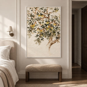 Branching gray-green leaves and pale yellow-green fruit on cream in an artwork with a white frame, displayed in a bedroom near the bed.