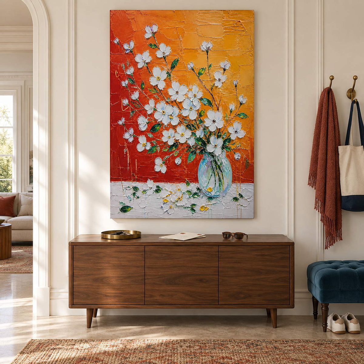 White blossoms in a glass vase against an orange and red background without an outer frame in an entryway.