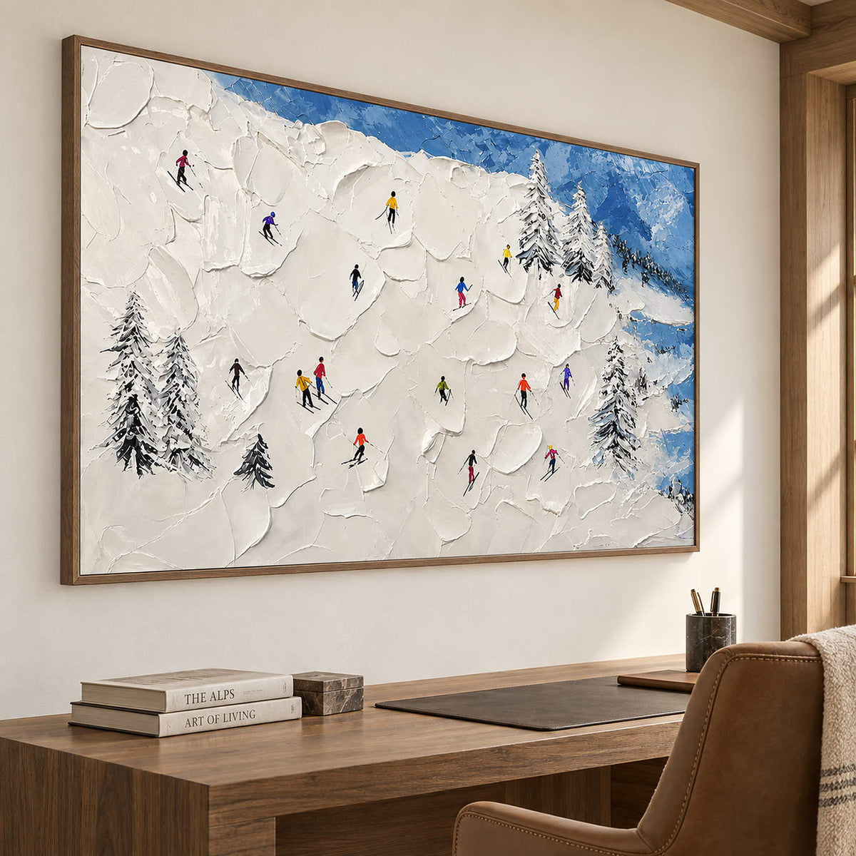 Hand-painted snowy mountain canvas with colorful skiers and pine trees, displayed in a study in a brown wood frame.