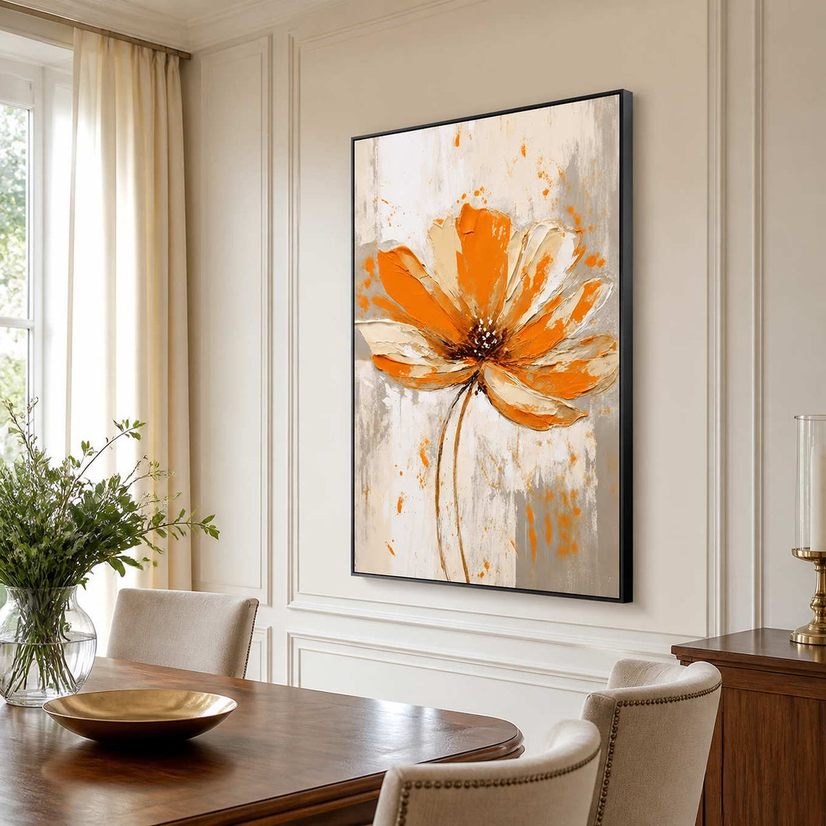 Black framed orange flower painting beside a wooden dining table with cream upholstered chairs.