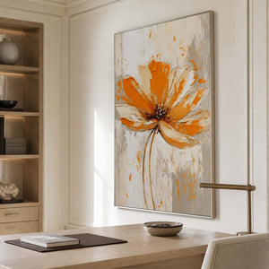 Silver framed orange flower painting above a pale wooden desk beside open shelves.