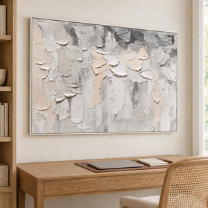 Overlapping ivory and gray raised strokes on a pale ground in a white frame, displayed in a home office.