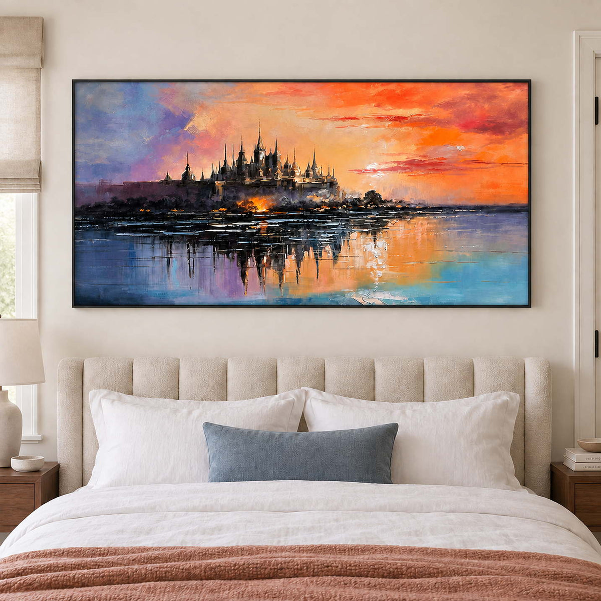A distant castle reflected in water beneath an orange sunset in a black frame, displayed above a bed.