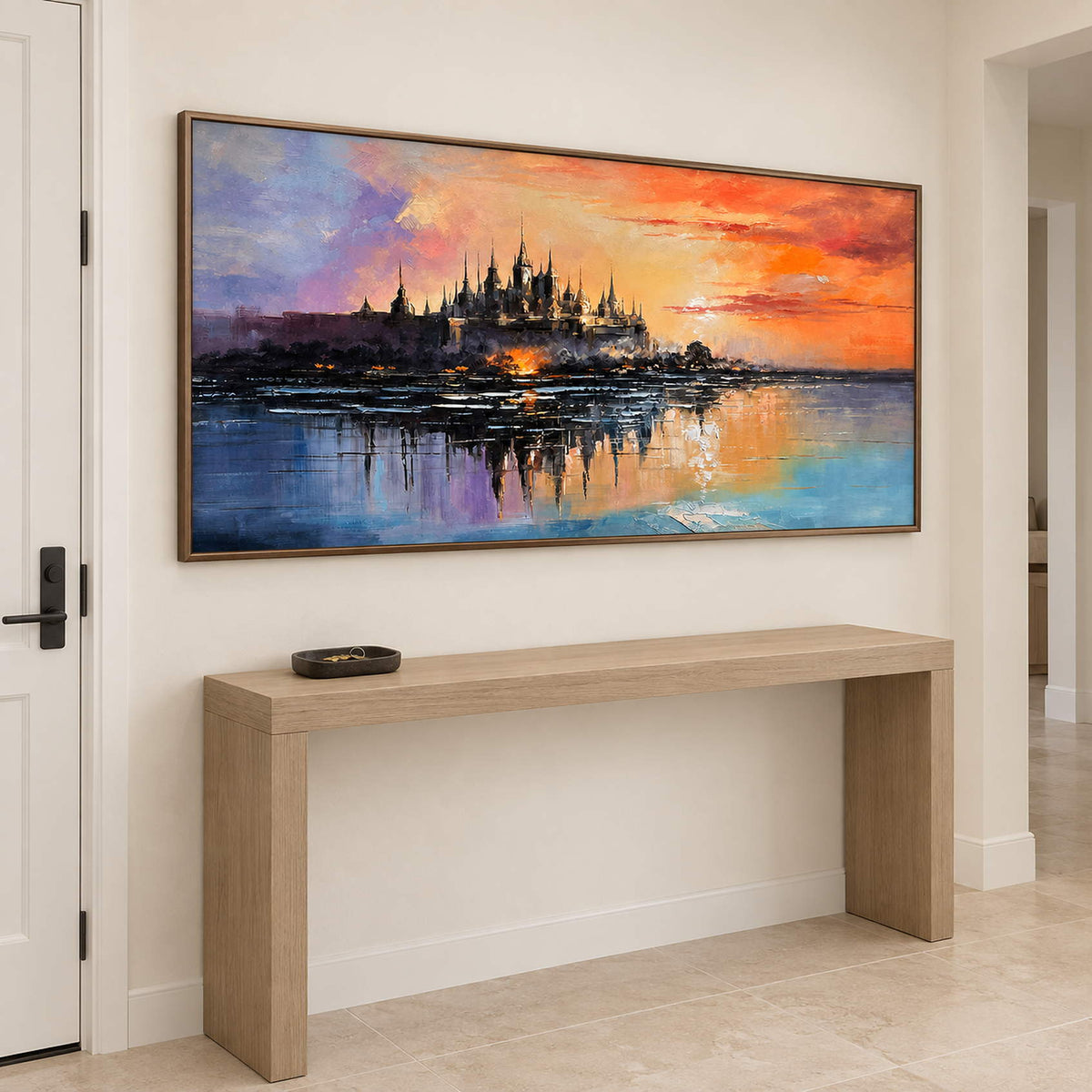 A distant castle reflected in water beneath an orange sunset in a brown wood frame, displayed above an entryway console.