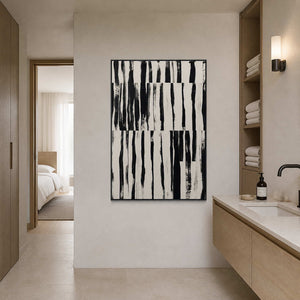 Black framed striped artwork beside a stone vanity and neatly stacked towels.