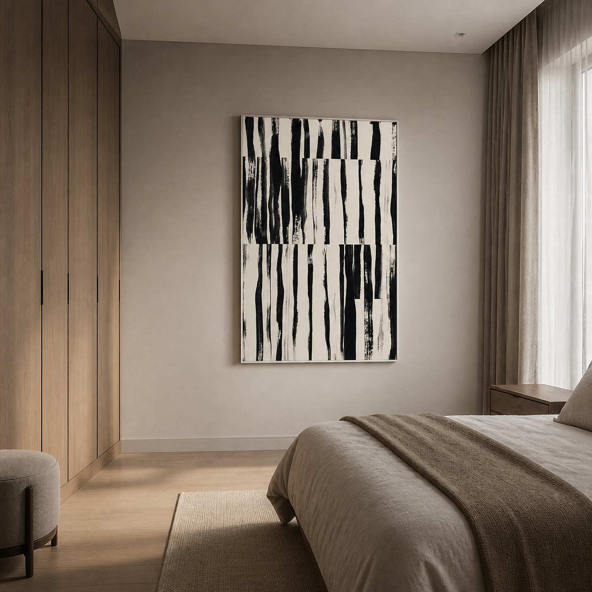 White framed black brushstroke artwork beside a bed with soft gray linens.