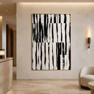 Gold framed black and white artwork near a hotel reception and rounded lounge chair.