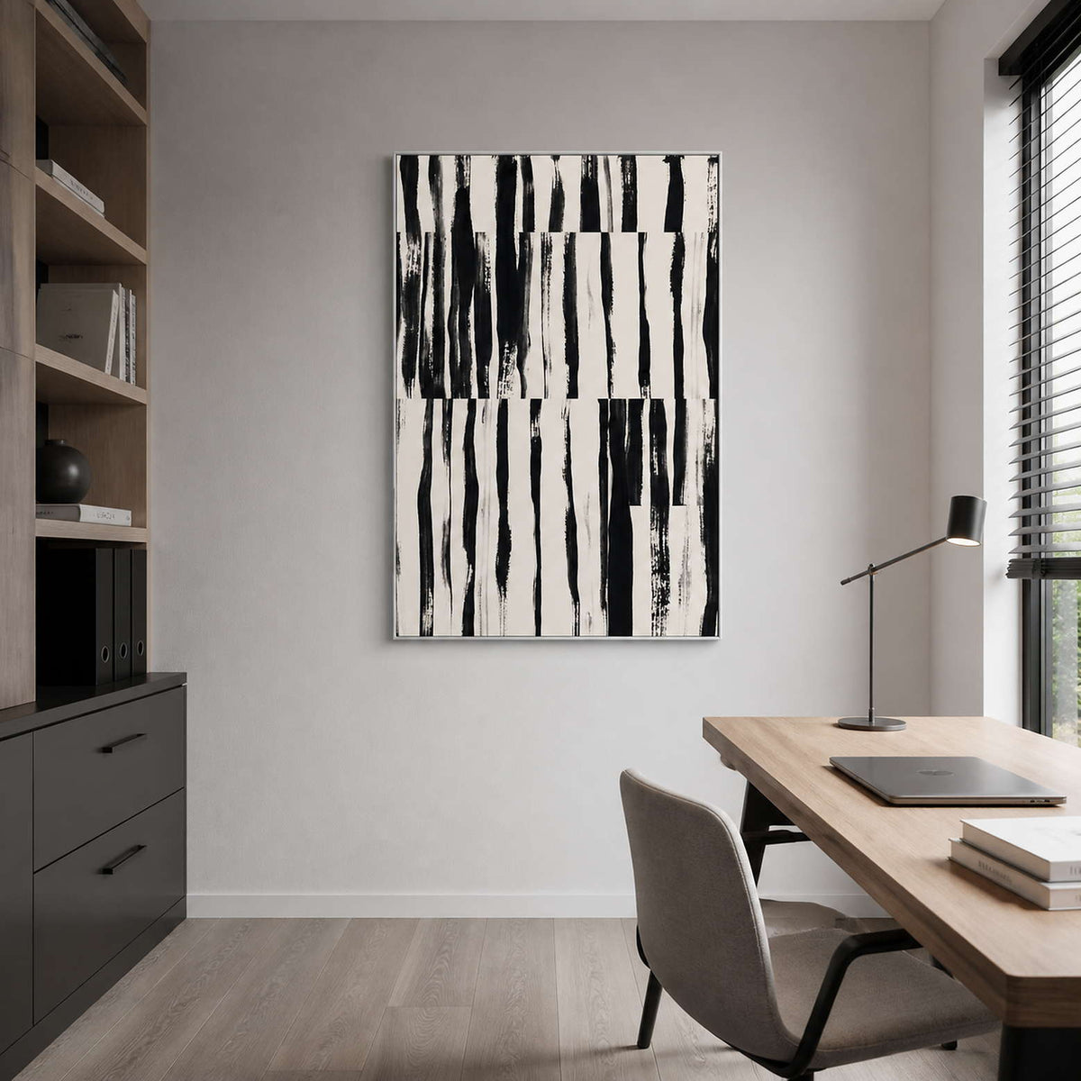 Silver framed black brushstroke artwork beside a home office desk and bookshelves.