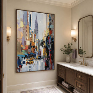 Wood framed colorful cityscape beside a bathroom vanity and a rounded rectangular mirror.
