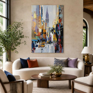 Frameless colorful cityscape above a cream sofa with blue and rust cushions.