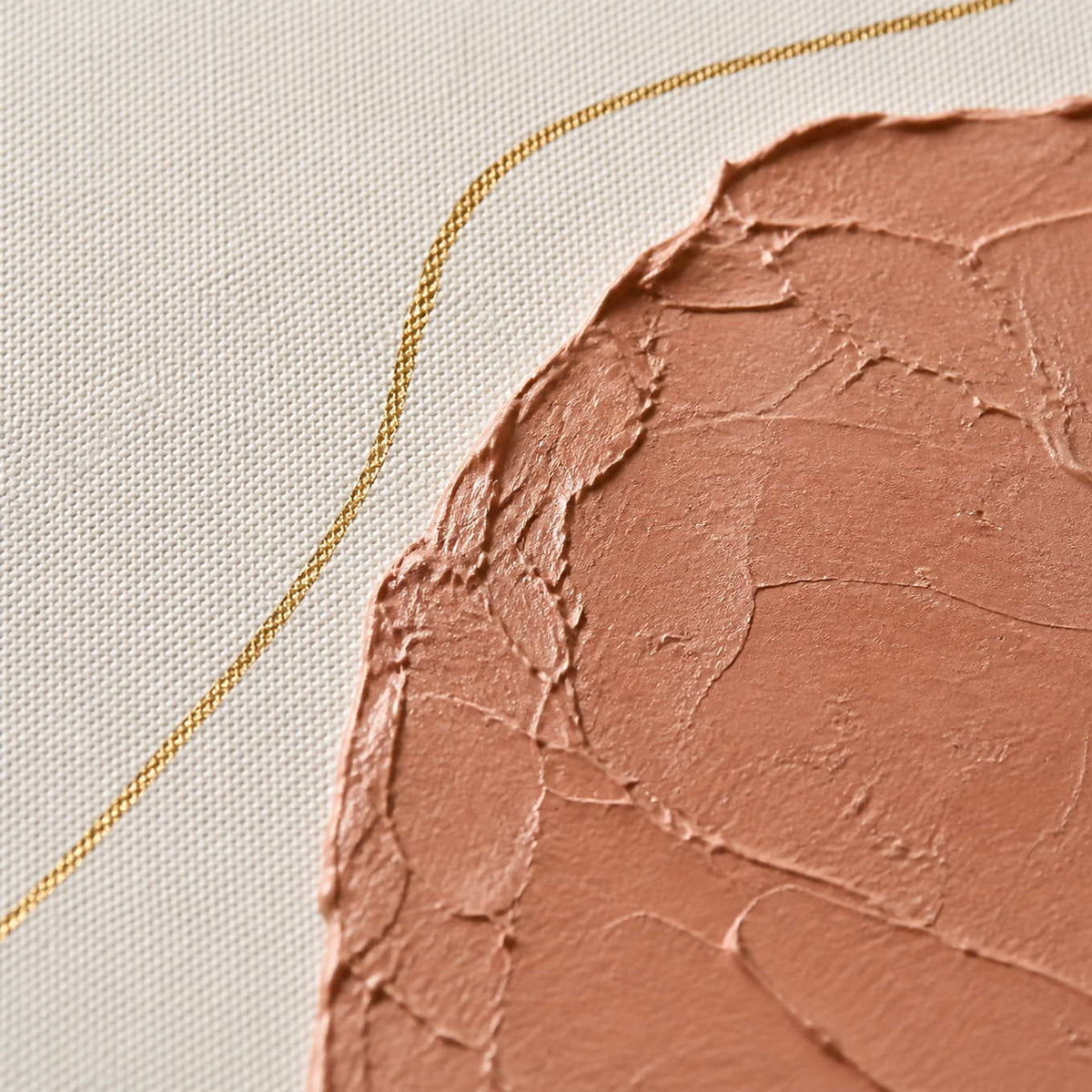 Close-up of raised terracotta plaster and a looping metallic gold line.