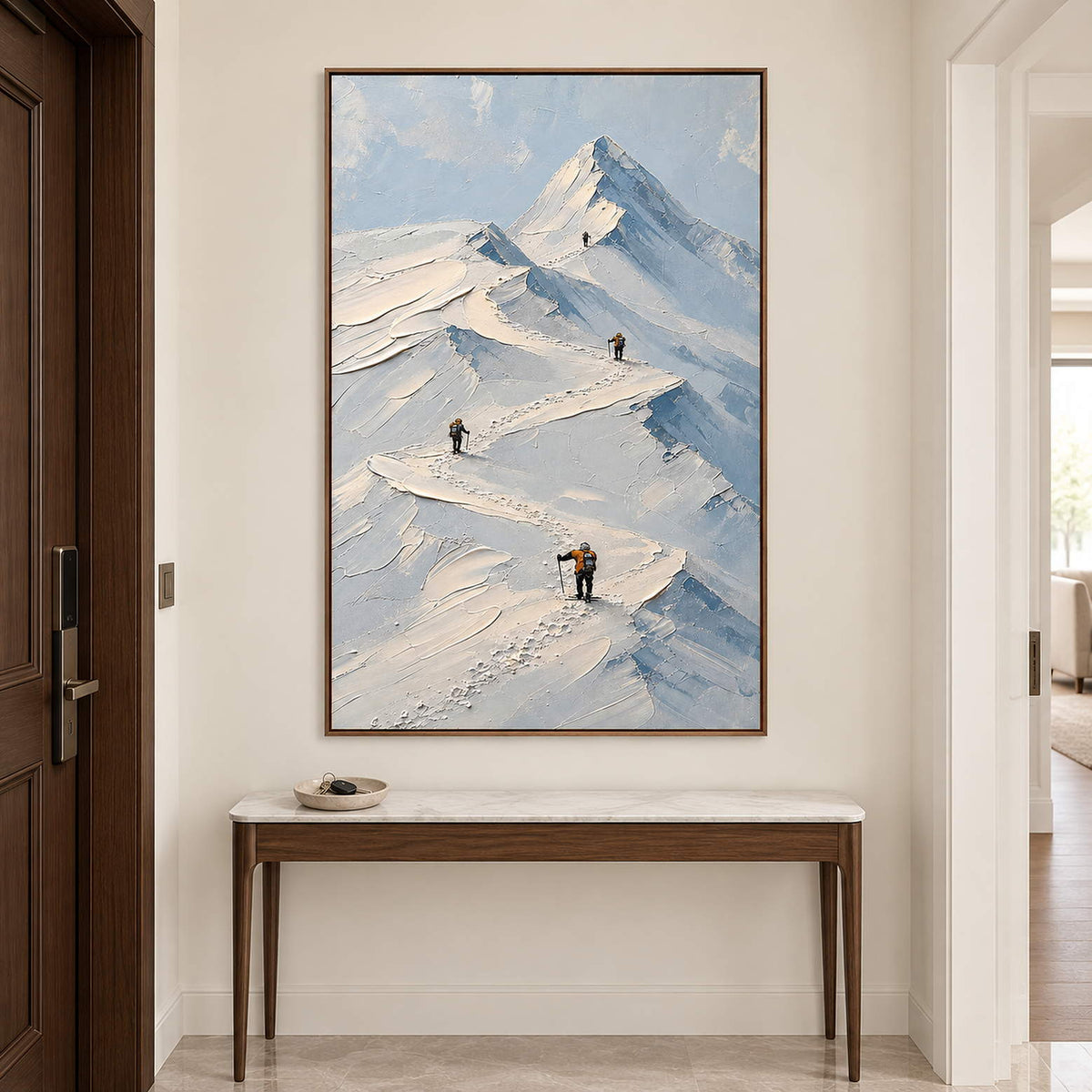 Small climbers following ridges across snowy mountains in a brown wood frame, displayed above an entryway console.