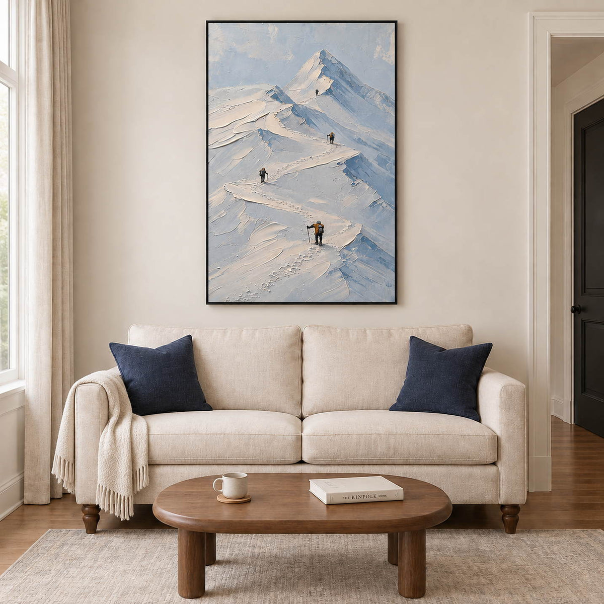 Small climbers following ridges across snowy mountains in a black frame, displayed above a sofa in a living room.