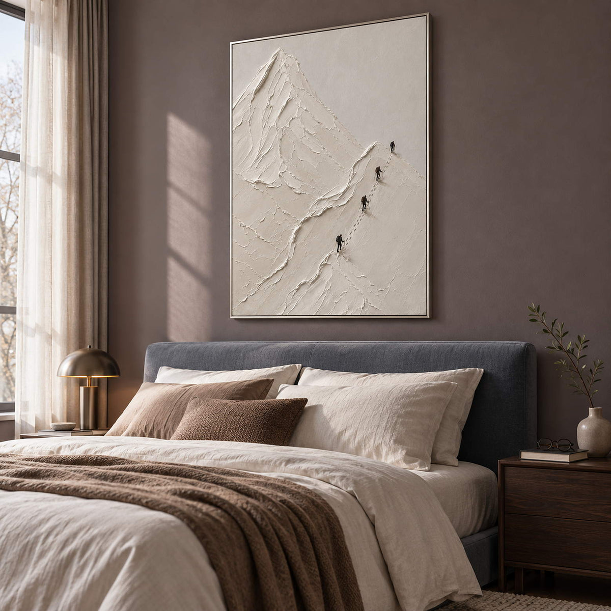 Four climbers ascending sculpted white mountain ridges in a vertical composition, displayed in a bedroom in a silver frame.