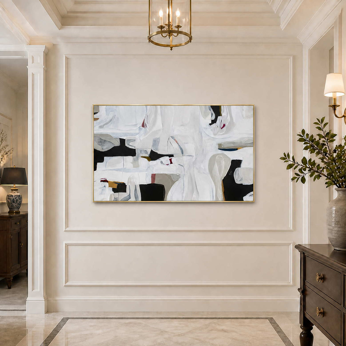 Gold framed white and charcoal abstract artwork on a softly illuminated paneled hallway wall.