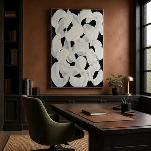 Gold framed abstract brushwork behind a wooden desk in a warm brown study.