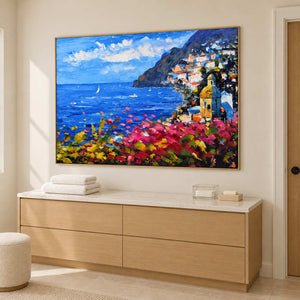 Angled coastal artwork above a pale cabinet holding folded towels.