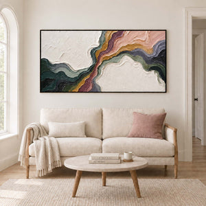 Flowing green, blush, ochre and charcoal bands through white texture in a black frame, displayed above a sofa in a living room.
