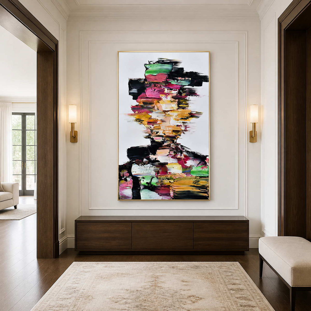 Gold framed multicolored portrait above a walnut console between illuminated sconces in an entrance.