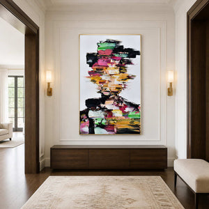 Gold framed multicolored portrait above a walnut console between illuminated sconces in an entrance.