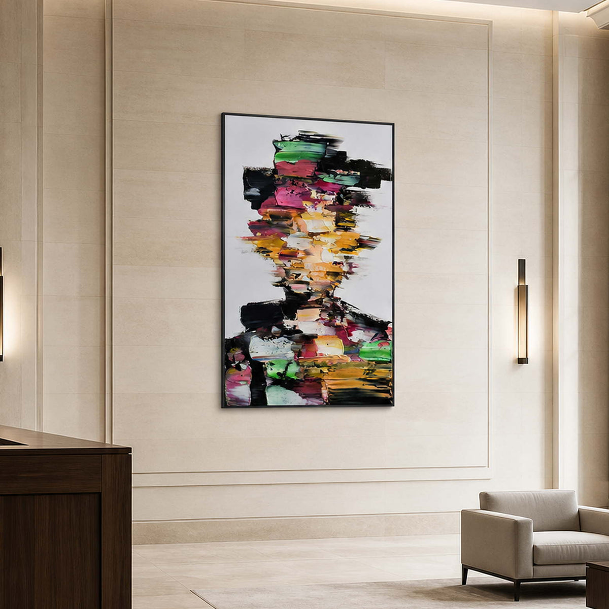 Black framed multicolored portrait on a pale stone wall beside a hotel lounge chair.