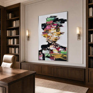 Silver framed colorful portrait between walnut bookshelves behind a wooden desk and leather chair.