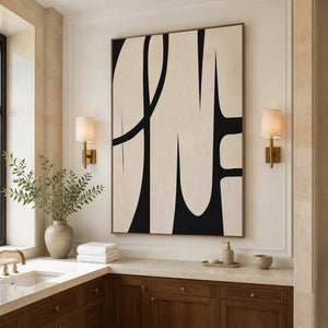 Wood framed cream abstract artwork between wall sconces above a pale vanity with wooden cabinetry.
