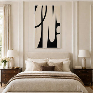 White framed cream and black curved artwork above a warm neutral bed between matching lamps.