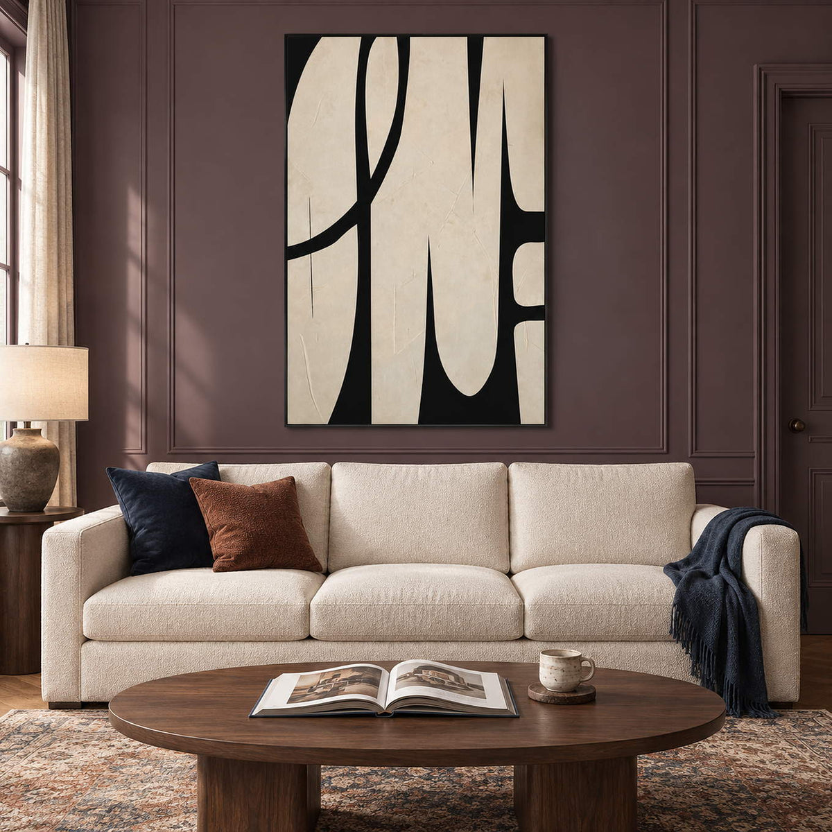 Cream and black abstract painting with elongated forms and a sweeping arc in a black frame in a living room.