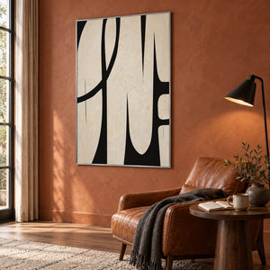 Cream and black abstract painting with elongated forms and a sweeping arc in a silver frame in a reading room.
